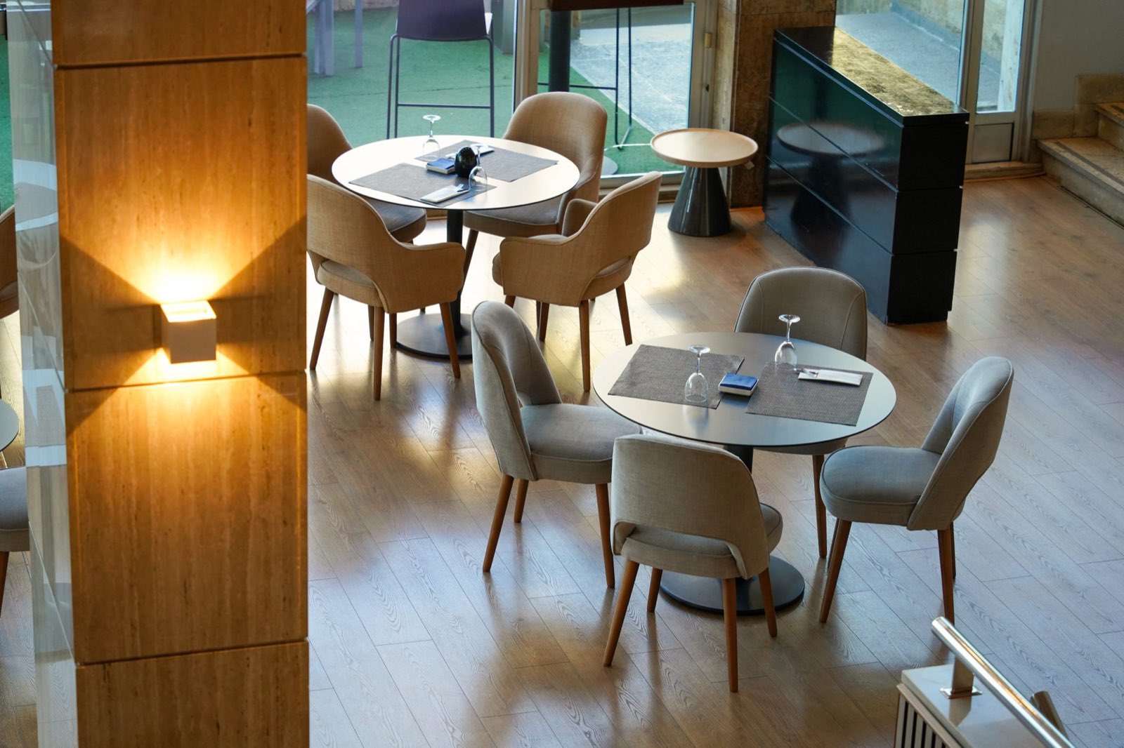 A calm, modern café interior with round tables and upholstered chairs